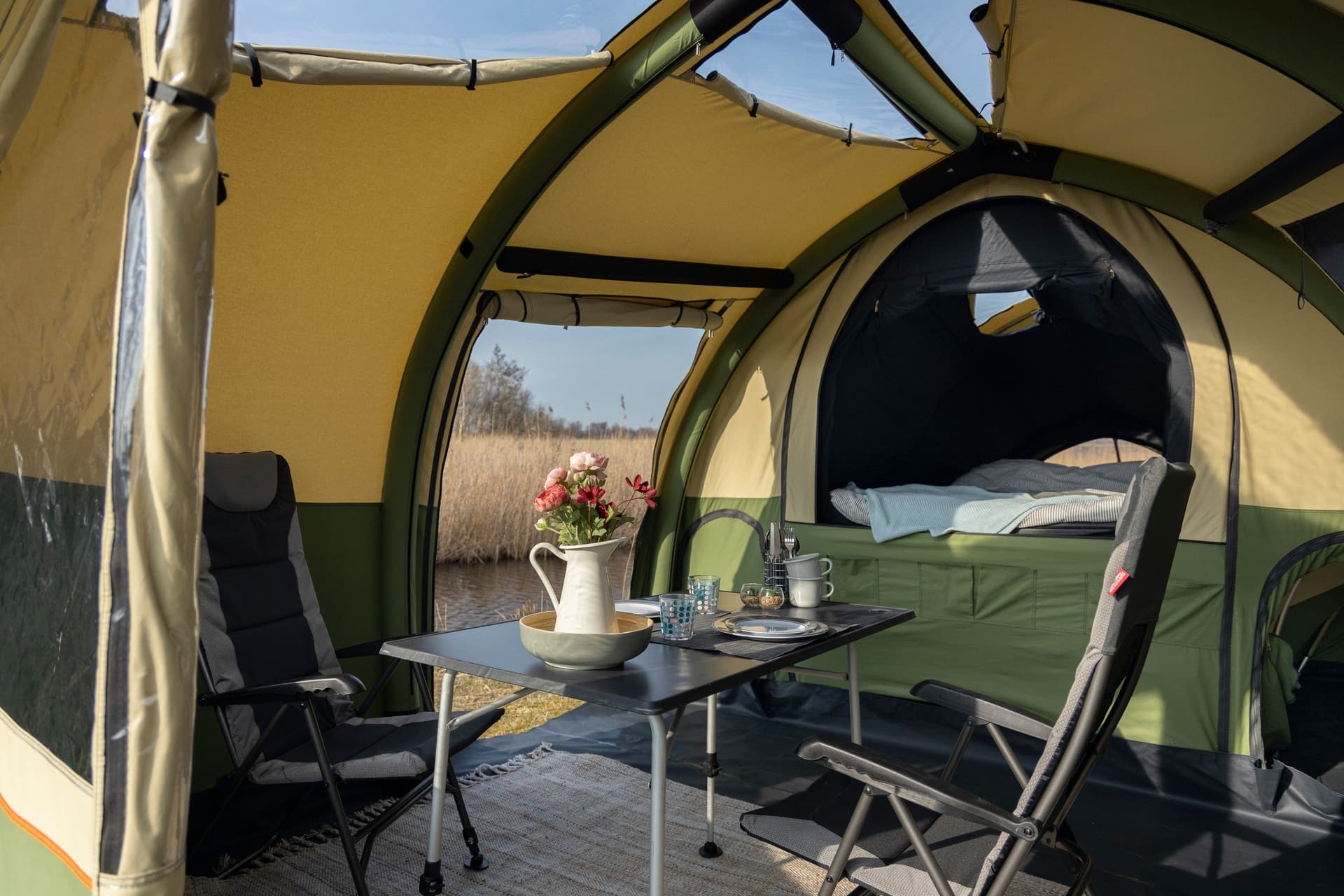 Interior of a trailer tent with open door and camping furniture